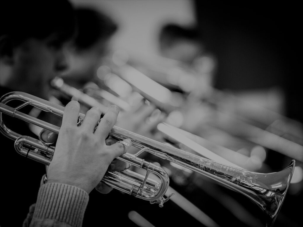 Närbild på flera som spelar trumpet på en lång rad
