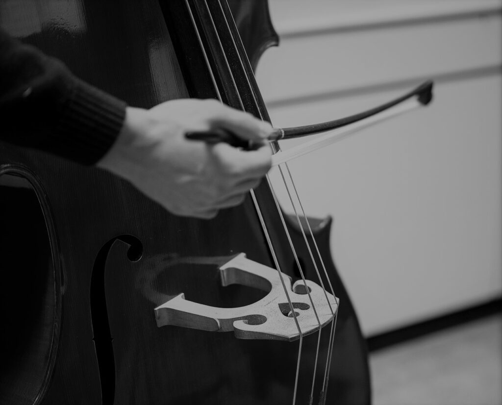 Närbild på en person som spelar cello. Man ser hand och stråk.