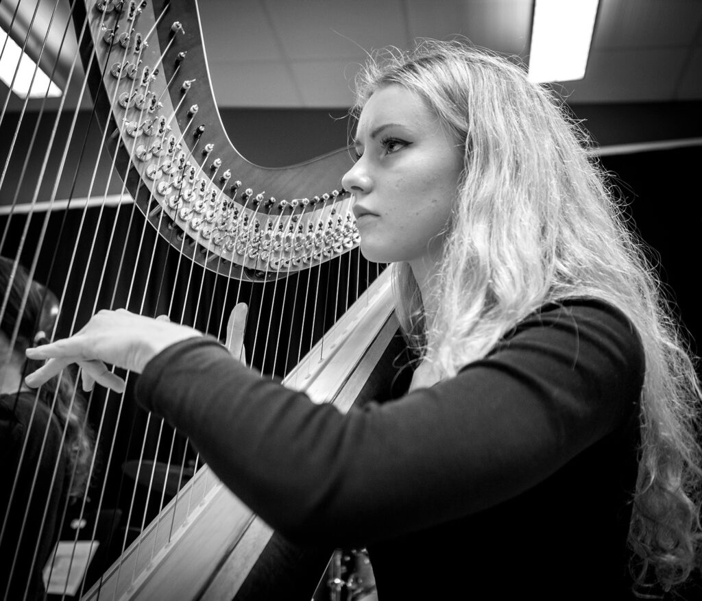 Ung tjej spelar harpa och tittar framåt