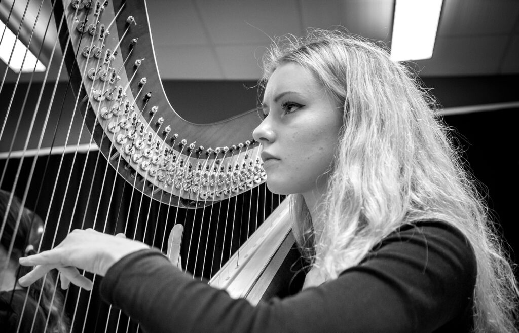 Ung tjej spelar harpa och tittar framåt